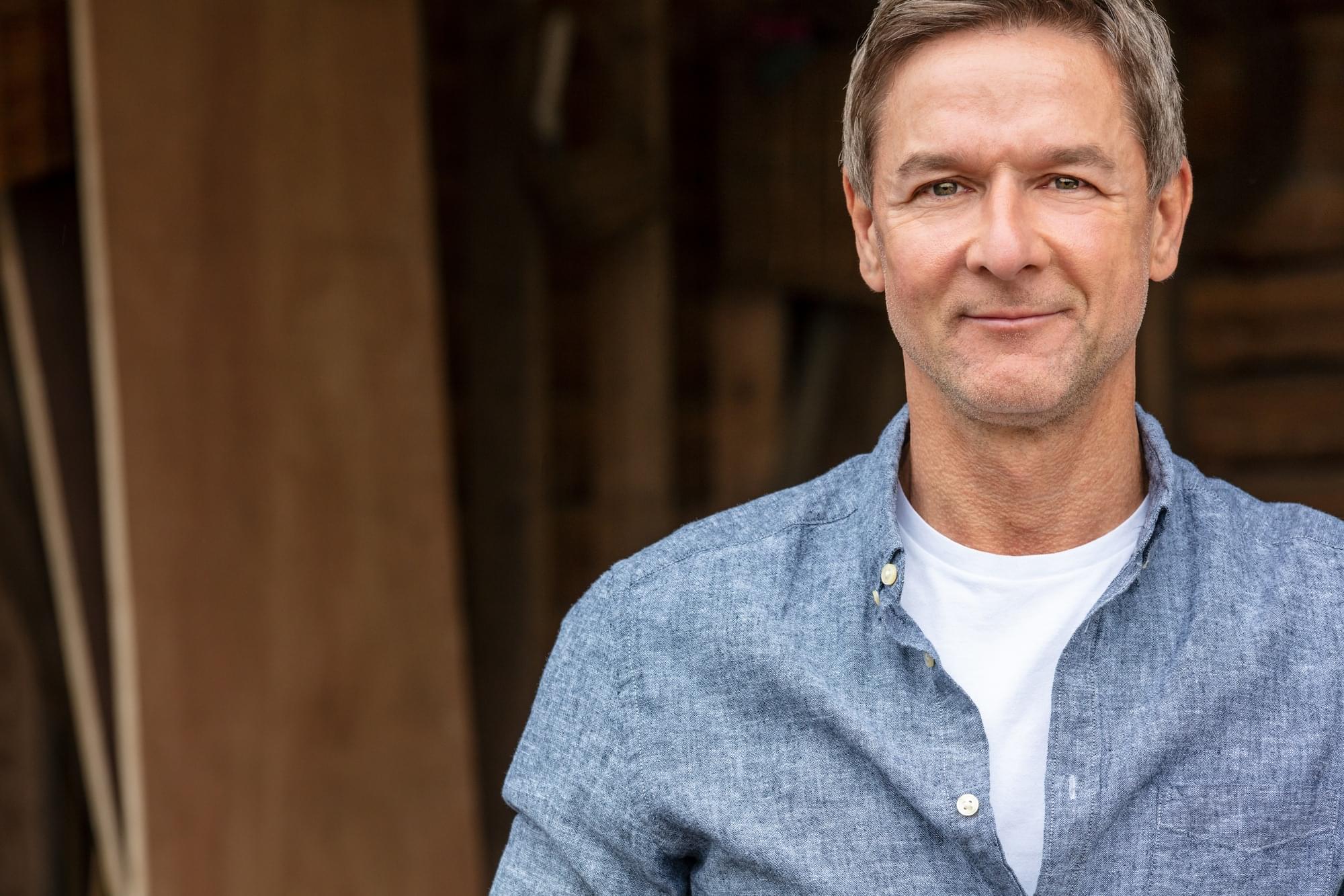 Happy Middle Aged Man Outside Portrait shot of an attractive, successful and happy middle aged man male wearing a blue shirt leaning on a post by a garage or barn
