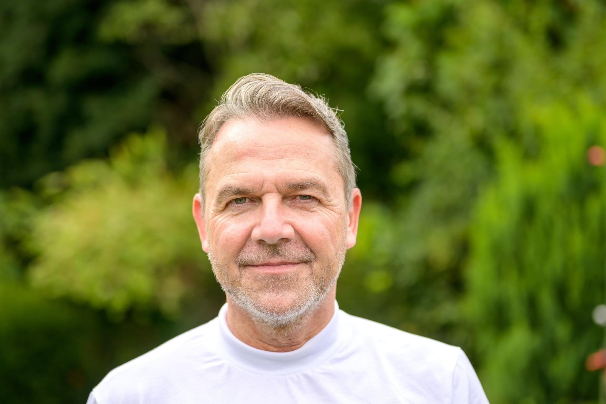 Close up Portrait of a man in his fifties with a gentle smile Close up Portrait of an attractive middle aged man in his fifties with a gentle smile while standing in the garden
