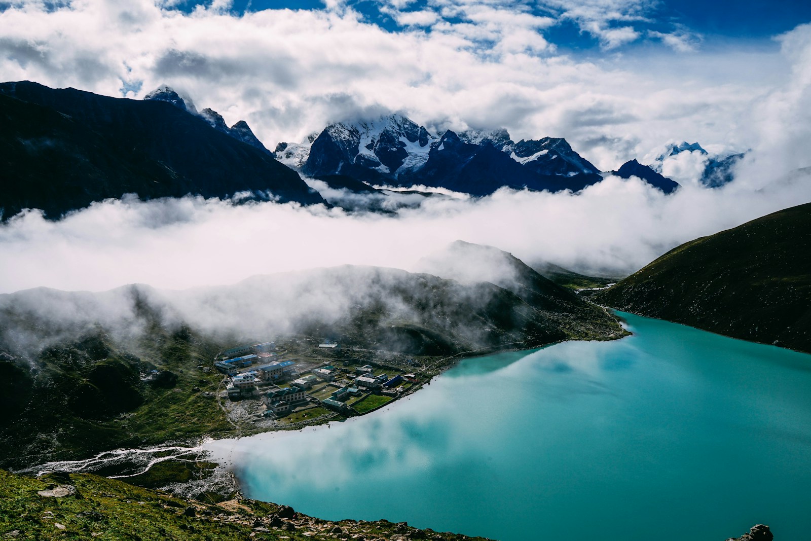 Photo by Chinh Le Duc calm lake on green tree-covered mountains under cloudy skies